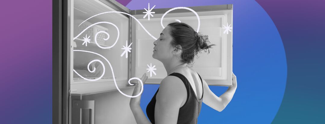 A woman fans herself as she stands in front of a freezer